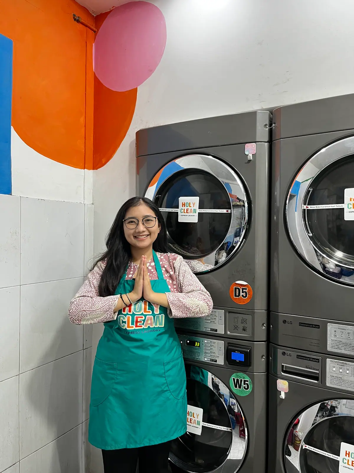 Staf Holyclean menyambut dengan salam di depan deretan mesin cuci